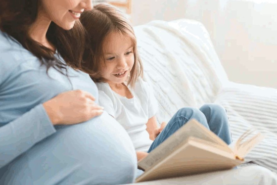 Pregnant mother reading to her daughter and her unborn baby.